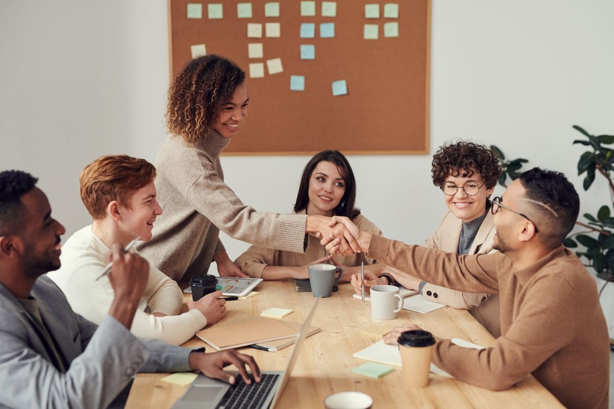 Two colleagues shaking hands across a busy meeting table